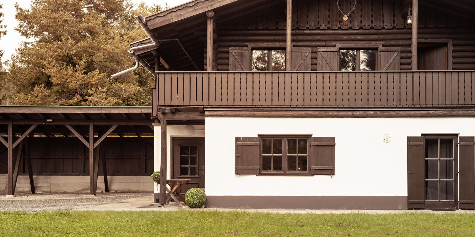 Die Vorderansicht des Chalet Franz aus der Nähe: Balkon, Fensterläden und der Hauseingang mit dem überdachten Carport an der Seite.