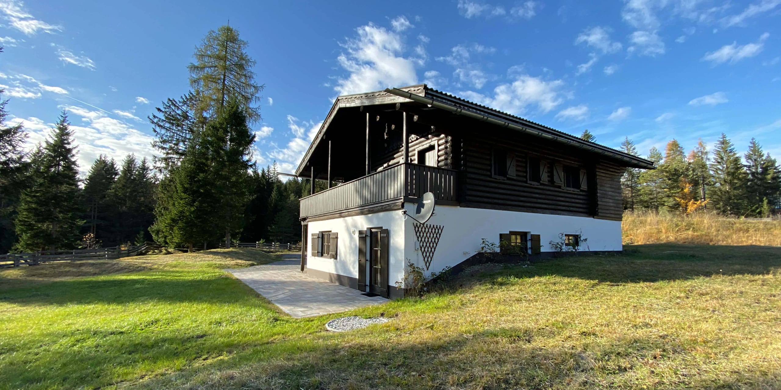 Das Chalet Franz auf seiner Wiese am Waldrand, mit Balkon unter dem weit vorgezogenen Dach.